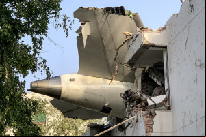 A parte traseira do voo 171 da Air India é fotografada no local após a queda em uma área residencial perto do aeroporto de Ahmedabad em 12 de junho de 2025. Um avião de ageiros com destino a Londres caiu na cidade indiana de Ahmedabad na quinta-feira e acredita-se que todas as 242 pessoas a bordo morreram, com o jato colidindo com prédios que abrigavam médicos e suas famílias. (Foto de Sam PANTHAKY / AFP)